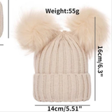 The Pret my baby Thick woollen double pompon beanie cap is a beige baby beanie with two fluffy pom-poms, measuring 16 cm tall, 14 cm wide, and weighing 55 grams.
