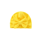 The Pret my baby cotton woven turban cap for babies features a bright yellow color and a large matching bow on the front, displayed against a plain white background.