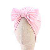 A mannequin head showcases Pret my baby’s cotton woven turban cap with a large bow in light pink, ideal for babies.
