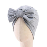 A mannequin head displays the Pret my baby - Cotton woven turban cap with a large bow, a light gray accessory by Pret my baby, perfect for babies.