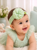 pretmybaby infant headband with a soft mint green layered flower and delicate lace leaves on a smiling baby girl