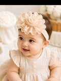 pretmybaby baby headband featuring a large layered pastel peach chiffon flower worn by an infant