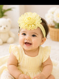 pretmybaby baby headband featuring a large yellow chiffon flower bud, worn by a smiling infant in a matching dress.