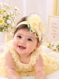 pretmybaby pastel yellow baby headband with a layered rose, butterfly, feathers, and pearls on a smiling infant