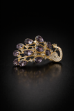 The Pretmebabe Peacock ponytail clutcher features purple gemstone feathers and clear crystals on gold, set against a black background—a striking accessory that pairs beautifully with elegant hairstyles.