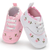 Two Pret my baby Embroidery sneakers—one pink, one white—stand upright on a white background, each adorned with small embroidered pink flowers and finished with white laces.