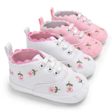 Four pairs of Pret my baby Embroidery sneakers - pink pre-walker shoes are displayed: two white with pink floral embroidery in front and two pink with similar designs behind, all featuring lace-up fronts and scalloped edges.