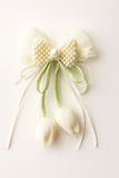 The Pret my baby Tulip with pearls and delicate ribbon fascinator hairclip features a cream bow adorned with pearls, lace, and ribbon, plus two white tulip buds—a charming accessory for any baby hair clip collection.