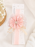 A Fancy fascinator vintage bow and pearls baby headband by Pret my baby is displayed on a white PRINCESS HAND MADE card. Perfect for infant hair accessories, the background features soft fabric and delicate white flowers.