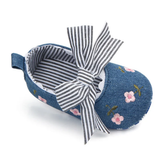 The Pret my baby Embroidery bellies with stripe bow - blue is a single baby shoe in blue denim with floral embroidery, a bold striped bow, striped lining, and a non-slip sole for added safety.
