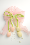 The Pret my baby Tulip with pearls large bow fascinator hairclip features three satin tulip buds, a pink ribbon bow, and strands of white pearls, making it perfect for handcrafted hair accessories.