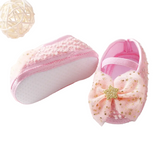 The Pret my baby Rosette bellies with star in pink feature a large mesh bow and gold glittery star; one shoe stands upright while the other reveals a textured white sole. A decorative ball accents the top left, making these shoes a delightful baby gift.