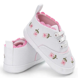 Pret my baby Embroidery sneakers - white: pre-walker baby shoes featuring pink scalloped edges and delicate pink flower embroidery, shown with one upright and one on its side.