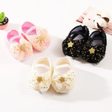 Three pairs of Pret my baby "Rosette bellies with star" in pink, black, and white are shown, each with a tulle bow and glittery gold star—ideal as a baby gift. A small panda figurine and round green pot appear in the background.