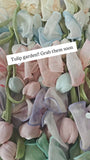 A close-up of Pret my baby’s Medium fascinator tulip bow shows pastel fabric tulips with green stems and delicate bows, arranged together like a charming mini garden. Grab yours soon!.