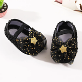 Pret my baby’s Rosette bellies with star in black are baby girl shoes adorned with large black tulle bows featuring gold star patterns and glittery gold star centers.